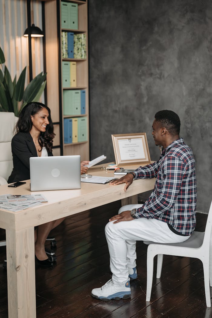 A professional office meeting between a smiling lawyer and client discussing documents.